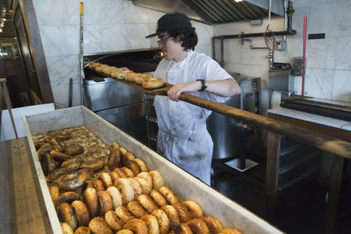 Baker Jefferson Arcila removes freshly baked bagels from the wood-burning oven at the Black Seed bagel shop in the East Village neighborhood of New York on May 27. (AP-Yonhap)