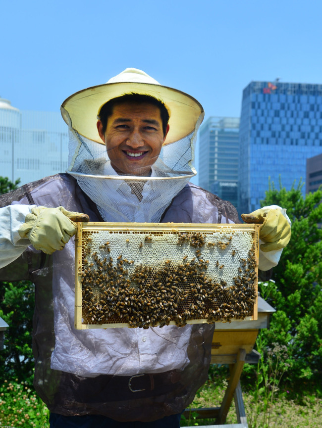Park Jin, founder of social enterprise Urban Bees Seoul, holds a beehive at the rooftop apiary located on the roof of UNESCO House in Myeong-dong on May 30. (Yoon Byung-chan/The Korea Herald)