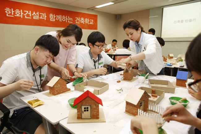 한화건설은 지난 7일 서울 영등포구 한화건설 본사에서 서울 봉림중학교 학생들을 초대해 ‘한화건설과 함께하는 건축학교’ 프로그램을 진행했다. 학생들이 한화건설 직원들의 지도를 받으며 모형을 이용해 직접 집을 짓고 있다.   [사진제공=한화그룹]