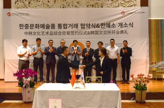 Heads of Qingdao-based Artworks Exchange (left) and the Korea Culture and Artworks Exchange shake hands at the opening ceremony of the KCAE on Wednesday in Seoul. (KCAE)