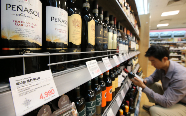 A customer checks out a wine at a discount store in Seoul.