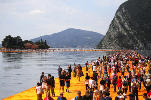 People walk on the monumental installation “The Floating Piers” by artist Christo Vladimirov Javacheff on Iseo Lake in northern Italy on June 18. (AFP-Yonhap)