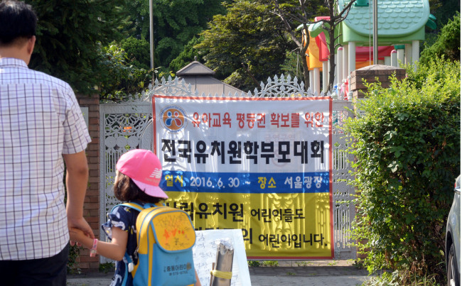어린이집에 이어 사립 유치원까지 집단 휴원에 나서면서, 맞벌이 부부 등 아이를 맡길 곳이 없는 학부모들만 골탕을 먹고 있다. 29일 한 학부모와 아이가 서울 마포구의 한 사립유치원에 등원하고 있는 가운데  유치원 한쪽 벽에는 30일 열리는 전국유치원학부모대회를 알리는 현수막이 붙어있다.   박현구 기자/phko@heraldcorp.com