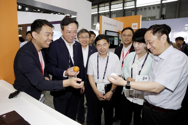 Jang Dong-hyun(second from left), the chief executive of SK Telecom, looks at products made by a Korean start-up at the MWC Shanghai 2016, a mobile trade show, on June 29.     SKT