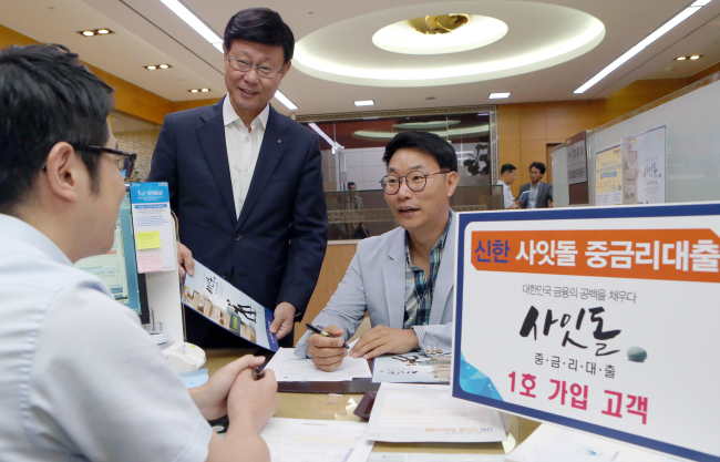 지난 5일 서울시 중구에 위치한 신한은행 영업부에서 신한 사잇돌 중금리대출 1호 신청자인 남대문 장칼국수 박영산 사장이 대출 신청 후 유동욱 부행장과 기념 촬영을 하고 있다.