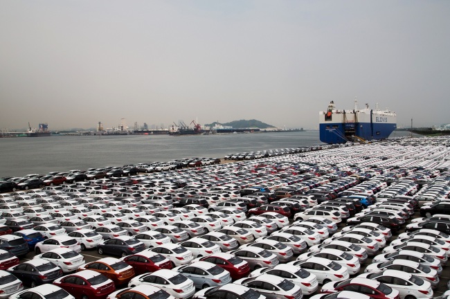 Hyundai Motor vehicles bound for export await shipment next to a Hyundai Glovis cargo ship at a port near Hyundai's plant in Ulsan on Tuesday./ The Investor