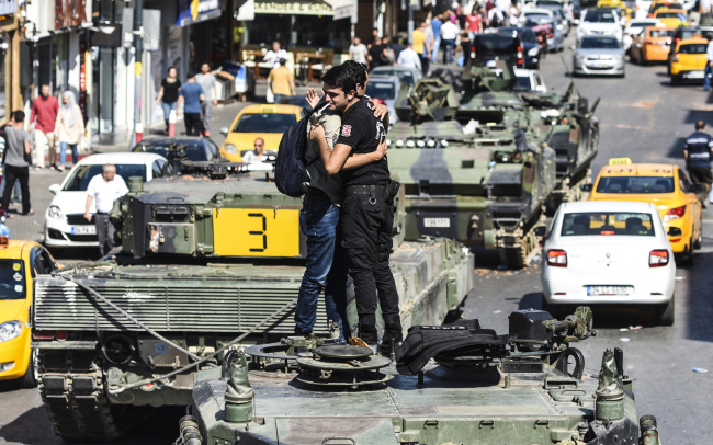 Turkish police officer (R) embrace a man on a tank after the military position was taken over at the Anatolian side at Uskudar in Istanbul on Saturday.President Recep Tayyip Erdogan urged Turks to remain on the streets on July 16, 2016, as his forces regained control after a spectacular coup bid by discontented soldiers that claimed more than 250 lives. Describing the attempted coup as a "black stain" on Turkey's democracy, Yildirim said that 161 people had been killed in the night of violence and 1,440 wounded. (AFP-Yonhap)
