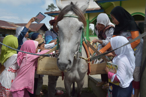 This picture taken on March 30 shows Indonesian children sorting books from a book shelf on Germanis as Ridwan Sururi (back left, in hat) compiles a list for his “moving library” for villagers in Serang, a quiet hamlet fringed by rice fields and a volcano on Indonesia‘s main island of Java. (AFP-Yonhap)