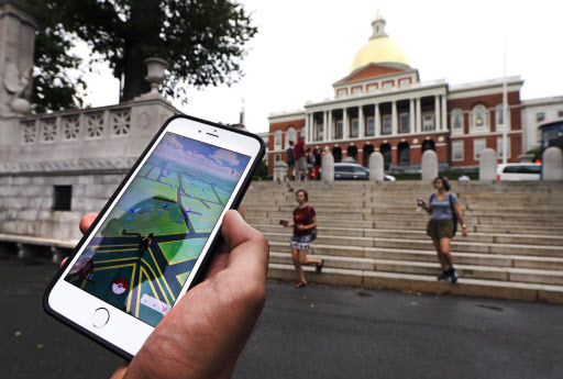 A “Pokemon Go” player shows his mobile phone while walking through the Boston Common, outside the Massachusetts Statehouse in Boston, on July 18. (AP-Yonhap)