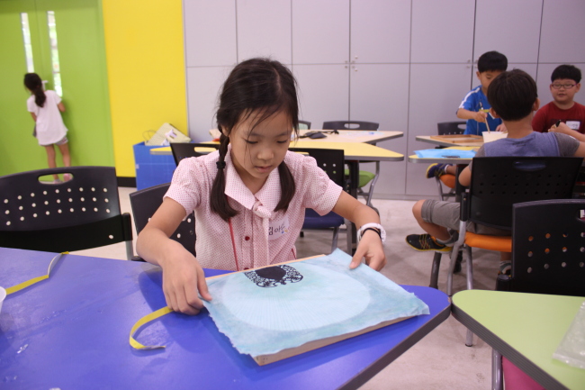 A child makes a fan using traditional mulberry paper at the National Folk Museum of Korea. (National Folk Museum of Korea)