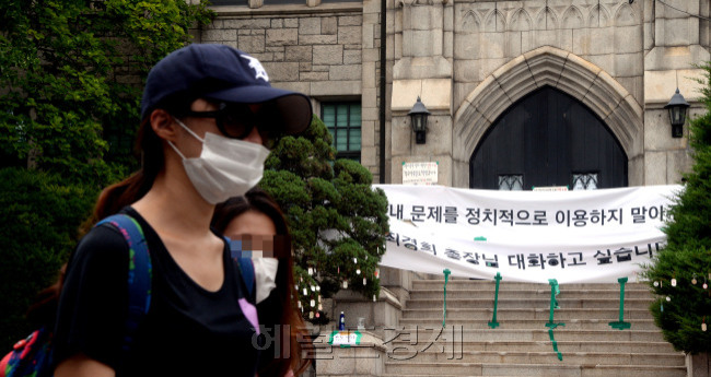 마스크와 선글라스를 한 본관 점거 농성자가 이화여대 본관 앞을 지나고 있다.
박현구 기자/phko@heraldcorp.com