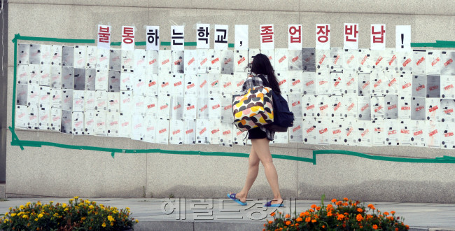이화여대 학생들이 학교 측의 평생교육 단과대학 사업 철회와 교육부의 수용 이후에도 총장 사퇴를 요구하며 농성을 이어갈 뜻을 밝힌 가운데 5일 오전 재학ㆍ졸업생의 본관 점거 농성이 9일째 계속되고 있다. 농성 중인 이화여대도 폭염은 비켜갈 수 없는 듯, 정문에 붙은 졸업장 반납 게시판 앞을 무더위에 대비해 간편한 차림을 한 여학생이 지나가고 있다. 박현구 기자/phko@heraldcorp.com