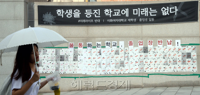 이화여대 학생들이 학교 측의 평생교육 단과대학 사업 철회와 교육부의 수용 이후에도 총장 사퇴를 요구하며 농성을 이어갈 뜻을 밝힌 가운데 5일 오전 재학ㆍ졸업생의 본관 점거 농성이 9일째 계속되고 있다. 농성 중인 이화여대도 폭염은 비켜갈 수 없는 듯, 정문에 붙은 졸업장 반납 게시판 앞을 무더위에 대비해 간편한 차림을 한 여학생이 지나가고 있다. 박현구 기자/phko@heraldcorp.com