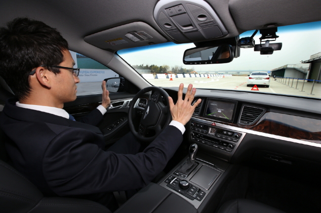 A driver sits behind the wheel of Hyundai Motor's self-driving Genesis sedan during a road testing event. Hyundai Motor