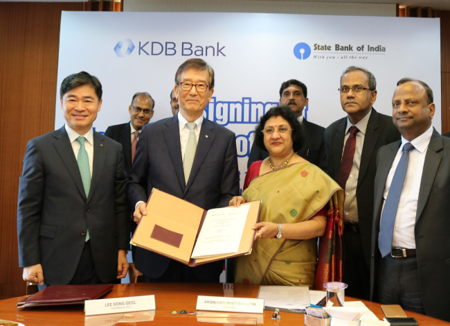 KDB chairman Lee Dong-geol (second from left, front row) and his SBI counterpart Arundhati Bhattacharya (third from left, front row) hold a memorandum of understanding document at the end of a signing ceremony in Mumbai, on Aug. 10.