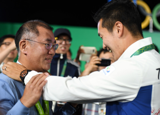 Korean archer Ku Bon-chan (right) hangs his medal to Chung Eui-sun, Hyundai Motor vice chairman, after his victory on Friday in Rio. Chung is the chairman of Korea Archery Association. (Yonhap)