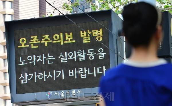 [사진설명= 올해 유난히 서울시에 오존주의보 발령(26회)이 집중되면서 폭염 만큼이나 여름철 건강에 적신호가 켜졌다. 오존주의보 발령 전광판 옆을 시민이 지나가고 있다. ]