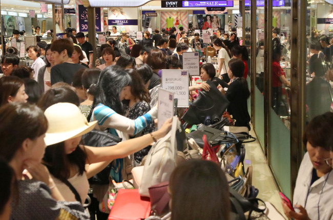 Customers shop at the Lotte Department Store in Myeong-dong, central Seoul on Sunday, where diverse foreign luxury goods are being sold at discounted prices as part of a clearance sale. Korean shoppers have been heading indoors to local department stores lately, to avoid the heat wave that has swept the nation over the past few weeks. (Yonhap)