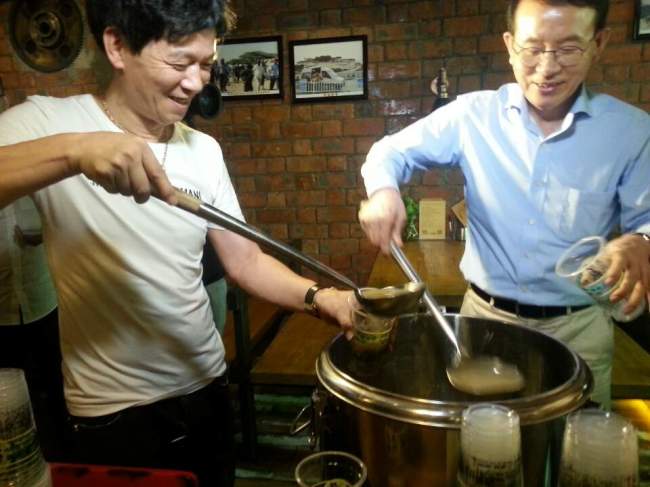 장청량(왼쪽) 사장과 민병철 선플재단 이사장이 길거리에서 환경미화원들에게 나눠줄 콩국물을 담고 있다.
