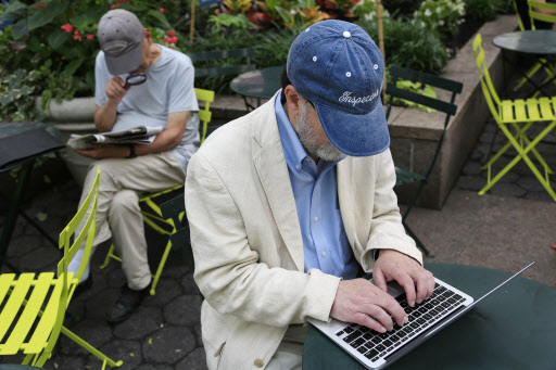 The author and former intelligence official who uses the name James Church in public works on his laptop in a New York park on June 29, 2016. (AP-Yonhap)