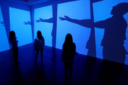 Visitors view a four-part video installation on Wednesday at the ninth Seoul International Media Art Biennale taking place at Seoul Museum of Art. (Yonhap)