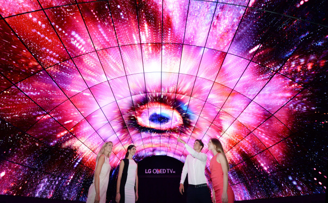 Models pose inside a tunnel illuminated with images from organic light-emitting diode screens. LG Electronics