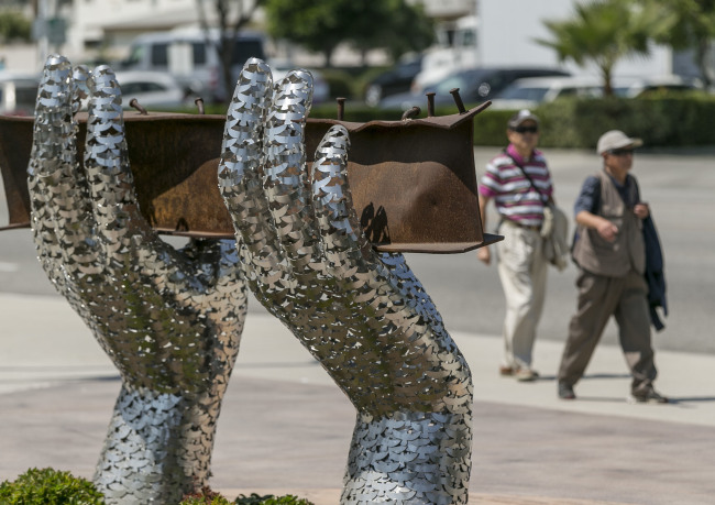 Pedestrians walk by artist Heath Satow’s sculpture “Reflect,” made with a damaged, rusted I-beam from the collapsed World Trade Center buildings, outside the Rosemead, California, city hall plaza. (AP - Yonhap)