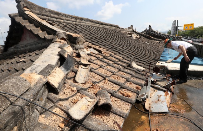 A man inspects the tile roof of his traditional Korean style house or hanok on Sept. 13 after a magnitude 5.8 earthquake hit the city of Gyeongju, North Gyeongsang Province a day before.