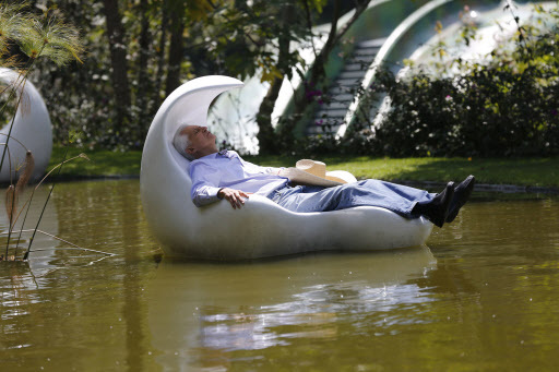 Architect Javier Senosiain sits in a hand-like fiberglass floating chair in the middle of a pond that serves as part of a water treatment and rain-water collection system for his architectural project, the “Nest of Quetzalcoatl,” on the outskirts of Mexico City, on Sept. 14. (AP-Yonhap)