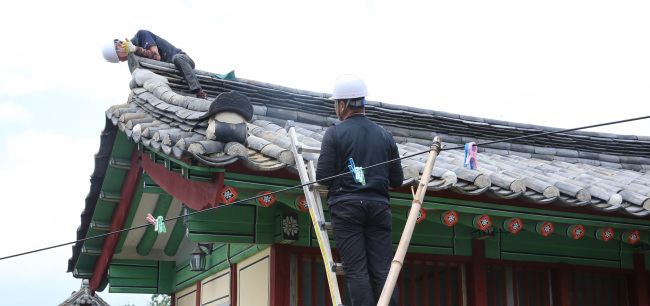 Workers on Wednesday repair roof tiles of Silla Kingdom-period Sungdeokjeon Shrine, which houses the ancestral tablet of King Park Hyeokgeose, damaged by the recent series of earthquakes. (Yonhap)