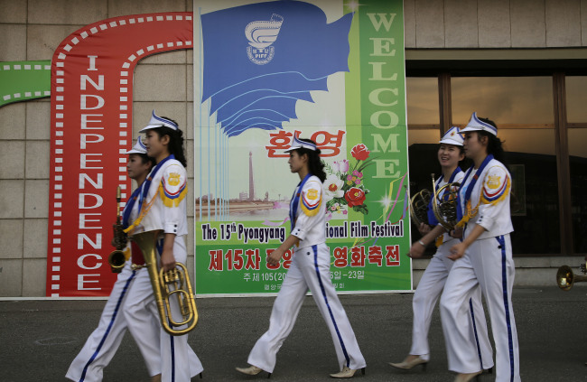 North Korean band members who performed at the Pyongyang International Film Festival walk past a sign at the venue where it was held, on Friday, Sept. 23, 2016, in Pyongyang, North Korea. (Yonhap-AP)