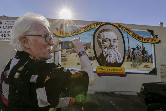 Canadian tourist Wayne Webb stops to take a photo of the mural “Waterman Junction Becomes Barstow, 1886,” on a building along Main Street in Barstow, California (Los Angeles Times/TNS)