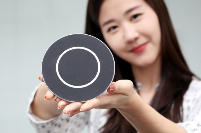 An employee of LG Innotek displays the firm’s 15-watt wireless charging pad for smartphones. LG Innotek