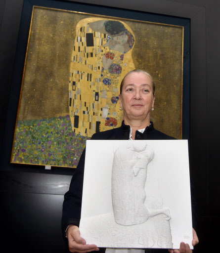 Belvedere manager Agnes Husslein-Arco poses with the tactile graphic of Gustav Klimt's “Kiss” in front of the original art work during a press conference to present the EU project “AMBAVis - Access To Museums For Blind And Visually Impaired People,” Wednesday, in Vienna, Austria. (AFP-Yonhap)