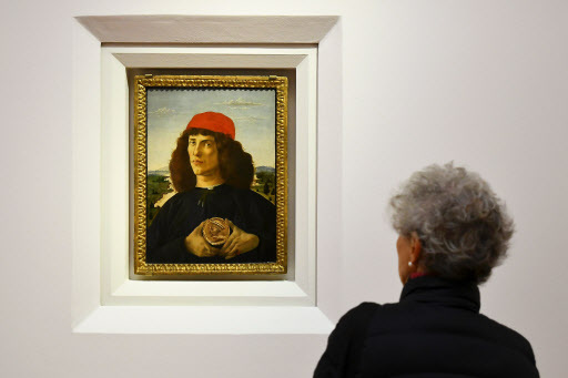 A woman looks at “Portrait of a Man with a Medal of Cosimo the Elder” painted around 1475 by Italian painter Sandro Botticelli during a press preview for the reopening of the rooms dedicated to Pollaiolo and Botticelli, at the Uffizi Gallery in Florence. (AFP-Yonhap)