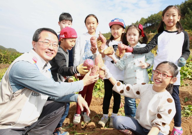 아시아나항공 김수천 사장(왼쪽 첫번째)이 김연두양(왼쪽 여덟번째)을 비롯한 임직원 자녀들과 함께 캔 고구마를 들어보이고 있다.  [사진제공=아시아나항공]