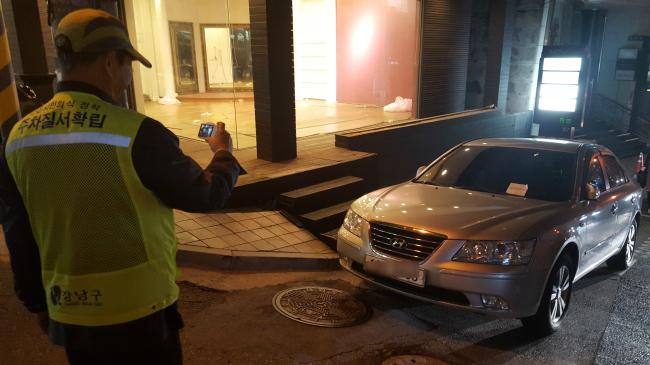 불법주차 단속원들이 서울 강남구 청담동 이면도로에서 대리주차 차량을 단속하고 있다(왼쪽 사진). 대리주차업체 직원으로 추정되는 시민과 단속원, 경찰관이 실랑이를 벌이고 있다.