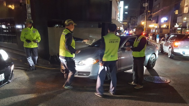 불법주차 단속원들이 서울 강남구 청담동 이면도로에서 대리주차 차량을 단속하고 있다(왼쪽 사진). 대리주차업체 직원으로 추정되는 시민과 단속원, 경찰관이 실랑이를 벌이고 있다.