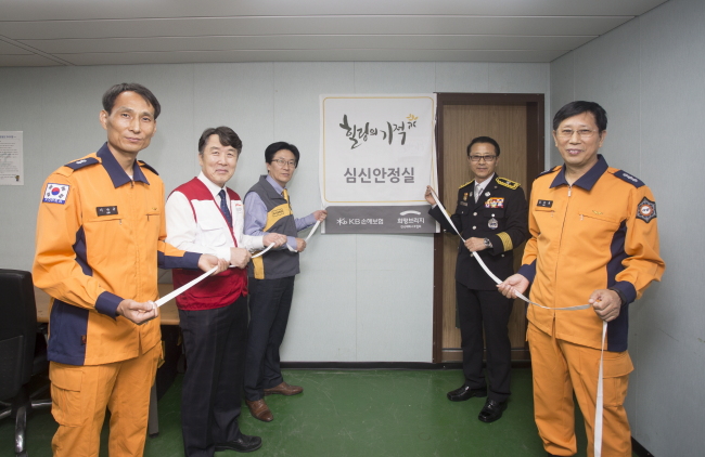 심신안정실 개소식에 참석한 KB손해보험 김태식 소비자보호본부장(왼쪽 세번째)과 희망브리지 전국재해구호협회 박영진 사무총장, 서울소방재난본부 김송연 안전지원과장, 119특수구조단 민춘기 단장, 뚝섬수난구조대 이낙규 지대장 등이 현판제막식을 진행하고 있다.