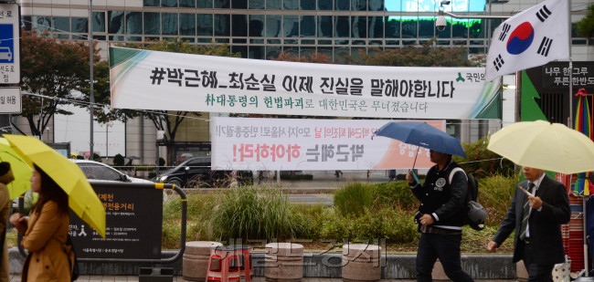 [사진=‘최순실 게이트’를 수사 중인 검찰이 31일 오후 3시 최 씨를 피의자 신분으로 소환 예정인 가운데, 31일 오전 서울 광화문에 걸린 최순실 게이트 관련 플래카드가 눈길을 끈다. 전날 이곳에선 2만여명(경찰 추산 1만2000여명)의 시민들이 참가한 촛불 시위가 열렸다. 우산을 쓴 시민들이 출근길을 재촉하고 있다. 박현구 기자/phko@heraldcorp.com]