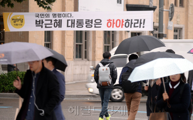 [사진=‘최순실 게이트’를 수사 중인 검찰이 31일 오후 3시 최 씨를 피의자 신분으로 소환 예정인 가운데, 31일 오전 서울 광화문에 걸린 최순실 게이트 관련 플래카드가 눈길을 끈다. 전날 이곳에선 2만여명(경찰 추산 1만2000여명)의 시민들이 참가한 촛불 시위가 열렸다. 우산을 쓴 시민들이 출근길을 재촉하고 있다. 박현구 기자/phko@heraldcorp.com]