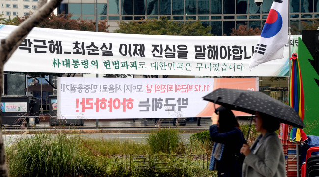 [사진=‘최순실 게이트’를 수사 중인 검찰이 31일 오후 3시 최 씨를 피의자 신분으로 소환 예정인 가운데, 31일 오전 서울 광화문에 걸린 최순실 게이트 관련 플래카드가 눈길을 끈다. 전날 이곳에선 2만여명(경찰 추산 1만2000여명)의 시민들이 참가한 촛불 시위가 열렸다. 우산을 쓴 시민들이 출근길을 재촉하고 있다. 박현구 기자/phko@heraldcorp.com]