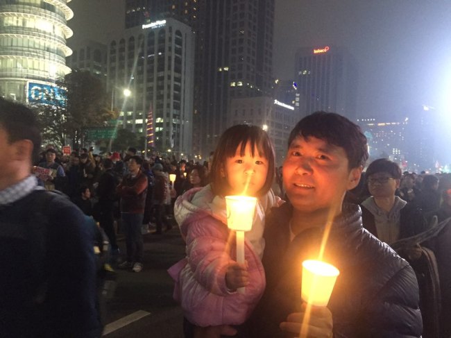 민중총궐기 투쟁본부 등 진보 진영 시민사회ㆍ노동단체들은 4일 오후 서울 종로구 광화문광장에서 ‘모이자! 분노하자! #내려와라 박근혜 2차 범국민행동’ 문화제가 광화문 광장에서 개최했다. 이날 집회에는 경찰 추산 4만5000여 명(주최 측 추산 20만여 명)이 모였다. 딸과 함께한 한 시민이 집회에 참석, 촛불을 들고 있다. 김진원 기자/jin1@heraldcorp.com