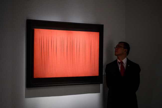 A security member looks at Lucio Fontana's ’Concetto Spaziale, Attese at “The Loaded Brush” display by auction house Christie‘s in Hong Kong on Nov. 23, 2016. (Yonhap-AFP)