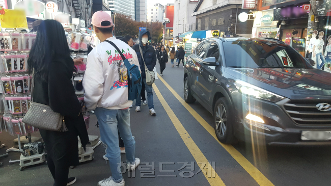 서울 마포구 홍대앞 거리의 모습. 불법 적치물이 놓인 골목에 차량이 지나가자 실제 보행자가 걸어다닐 수 있는 길은 1m도 되지 않아보였다. 불법 적치물이 기승을 부리는 이유가 계도 위주 행정 때문이 아니냐는 비판이 나온다. 보행 안전과도 직결된 만큼 단속 강도를 높여야 한다는 지적이다.