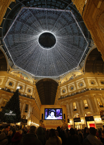 People watch a giant screen broadcasting the opening season gala of the Milan's La Scala opera theater, in downtown Milan, Italy, on Wednesday. (AP-Yonhap)