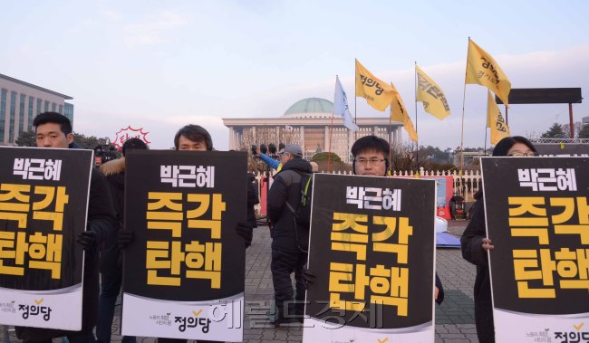 [사진설명=박근혜 대통령의 탄핵소추안 표결이 있는 9일, 시민들은 각기 탄핵에 대한 자신의 목소리를 내기 위해 국회 앞에 모여들었다. 국회 정문 앞에서 탄핵을 촉구하는 피켓을 들고 있는 시민들. 정희조 기자/checho@heraldcorp.com]