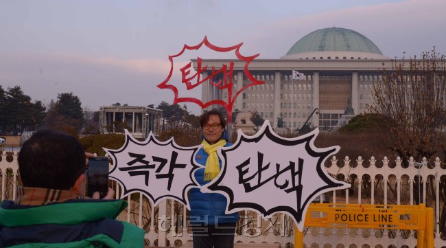 [사진=박근혜 대통령의 탄핵소추안 표결이 있는 9일, 시민들은 각기 탄핵에 대한 자신의 목소리를 내기 위해 국회 앞에 모여들었다. 국회 정문 앞에서 탄핵을 촉구하는 피켓을 들고 있는 시민들. 정희조 기자/checho@heraldcorp.com]