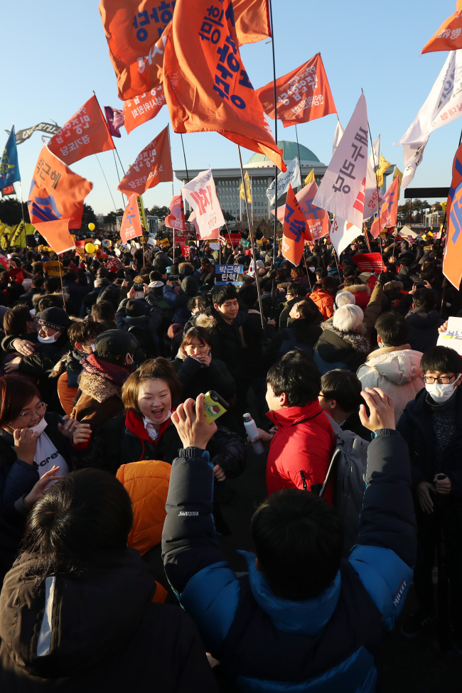 Citizens gathered in front of the National Assembly on Friday cheer after hearing that the motion for President Park Geun-hye's impeachment has been passed. (Yonhap)