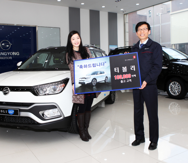 A SsangYong sales executive (right) poses with the owner of the 100,000th Tivoli in the carmaker’s branch in Balsan Seoul, Monday. (SsangYong Motor)